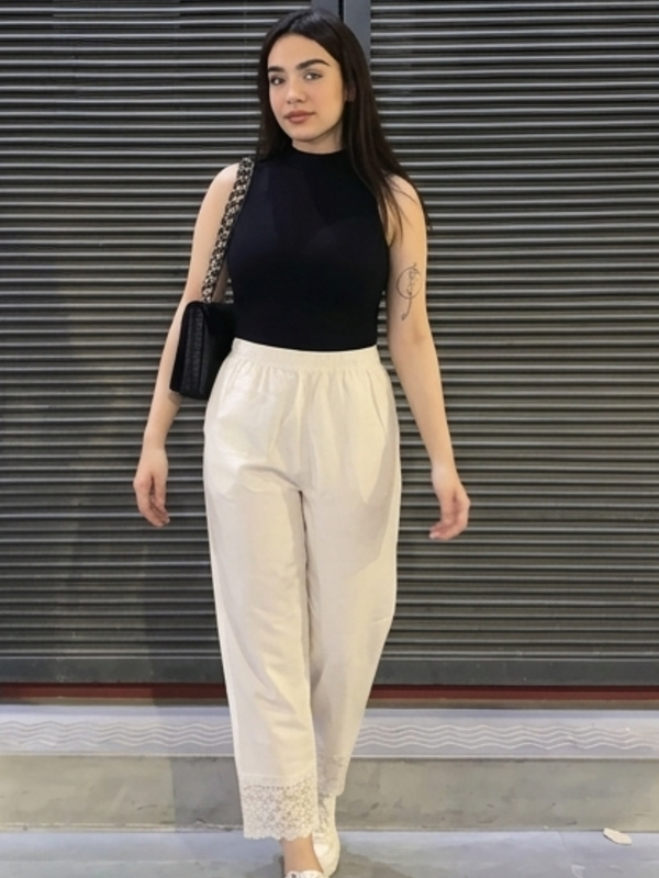 Close-up of lace hem detail on white palazzo